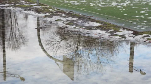 Reflection of basketball hoop and backboard in puddle during spring thaw Video stock 329640667