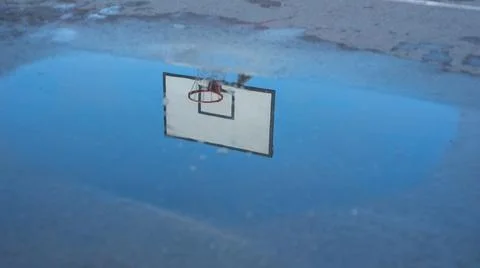 Reflection of a basketball ring in a puddle after the rain. Stock Photos