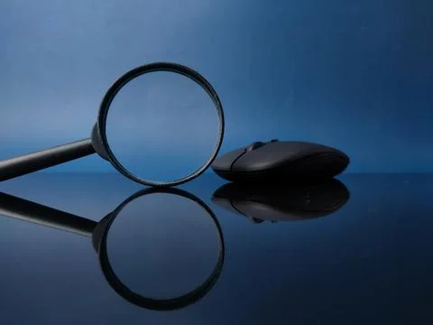 Reflection black mouse and magnifying glass on a black acrylic board Stock Photos