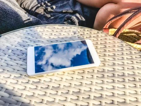Reflection of blue sky with clouds in the phone-smartphone, which lies on a b Stock Photos