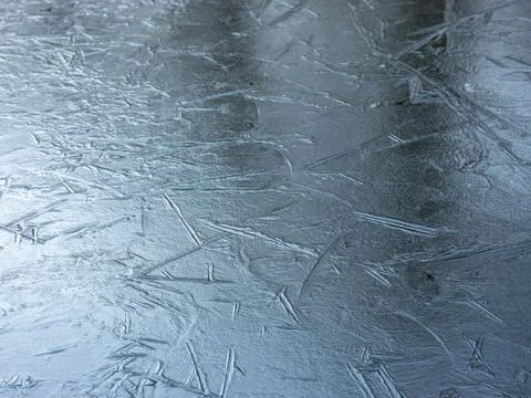 Reflection of blue sky in frozen surface of puddle with graphic lines Stock Photos