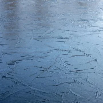 Reflection of blue sky in frozen surface of puddle with graphic lines Stock Photos