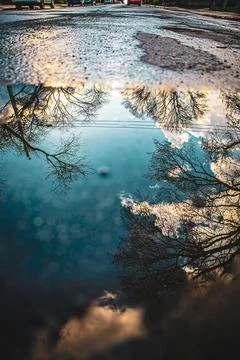 Reflection of blue sky on puddle at street Stock Photos