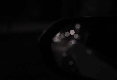 Reflection of bokeh in the side mirror of car. Vintage, film style. Black a.. Stock Photos