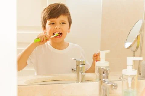 Reflection of boy in mirror during tooth brushing Stock Photos