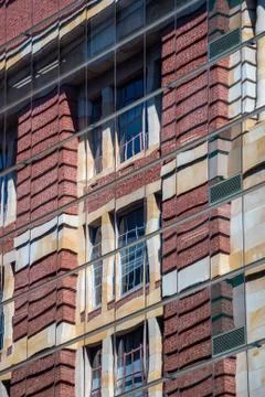 Reflection of brick building in modern skyscraper facade with reflective wind Stock Photos