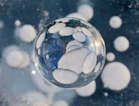 Reflection of bubbles in a glass ball lying on the ice Foto stock