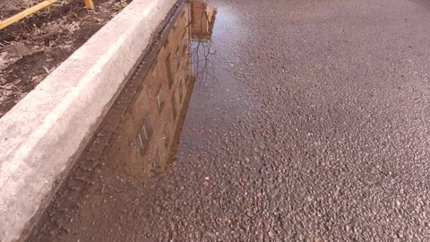 Reflection of the building and the sky in a puddle on the asphalt Stock Footage 240401407
