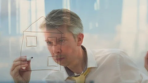Reflection of a businessman drawing an image of a house onto glass Video stock 80732216