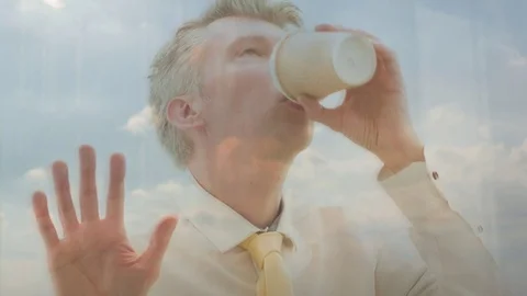 Reflection of a businessman looking out of a window drinking coffee Video stock 80744900