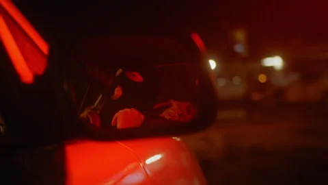 Reflection in a car mirror of a man pulling a ski mask over his face at nig.. Stock Footage 275174000