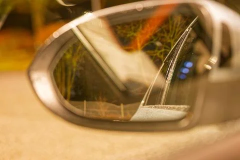 Reflection of a car side mirror showing a rainy window and blurred background Stock Photos