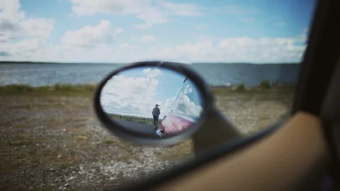 Reflection in the car's side view mirror of a woman getting into the car Stock Footage 80340229