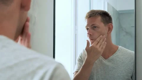 Reflection of Caucasian handsome young man applying moisturizing cream to face Stock Footage 266161171