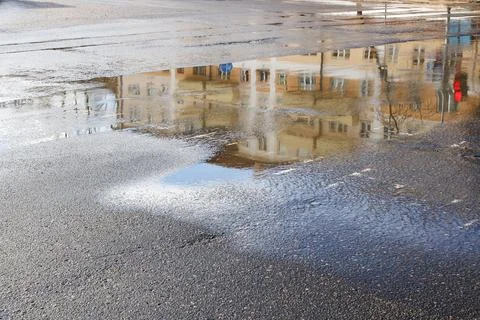 Reflection of city in puddle on pavement Stock Photos