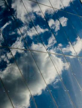 Reflection of clouds and blue sky in the glass wall of a modern business cent Stock Photos