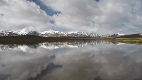 Reflection of clouds and mountains on a calm lake at Arabel Plateau, Kyrgyzstan Stock Footage 306568328