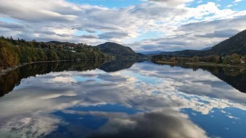Reflection of clouds and trees on calm water in a valley during daytime Stock Photos