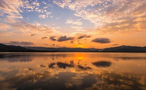 Reflection of clouds and twilight sky over clear water surface Stock Photos