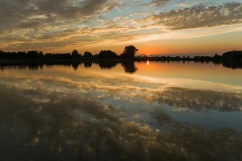 Reflection of clouds in a calm lake, view during sunset Stock Photos
