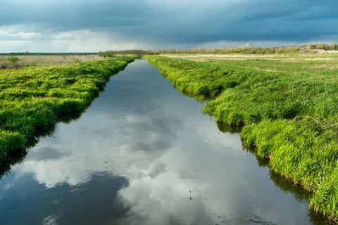 Reflection of clouds in a calm river with a green bank, Czulczyce, Poland Stock Photos