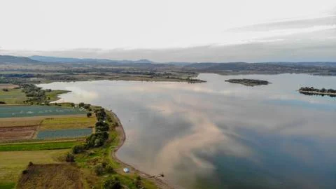 Reflection of clouds in the lake. Beginning of sunset. Stock Photos