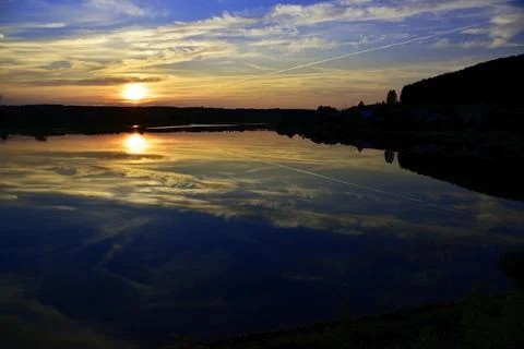 Reflection of clouds of summer sunset on calm water surface Stock Photos