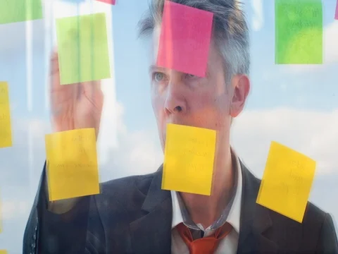 Reflection of a creative businessman putting post it notes on to a window Video stock 80171961