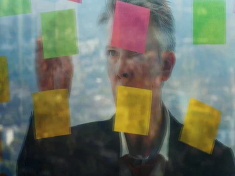 Reflection of a creative businessman putting post it notes on to a window Video stock 80172169
