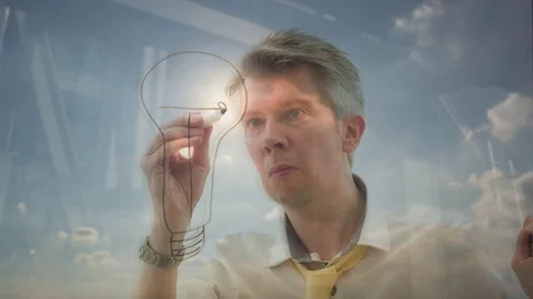 Reflection of a creative man drawing a lightbulb onto glass Video stock 80717906