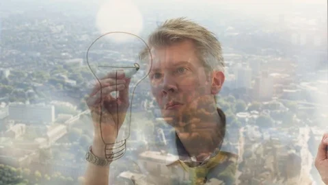 Reflection of a creative man drawing a lightbulb onto glass Video stock 80721032
