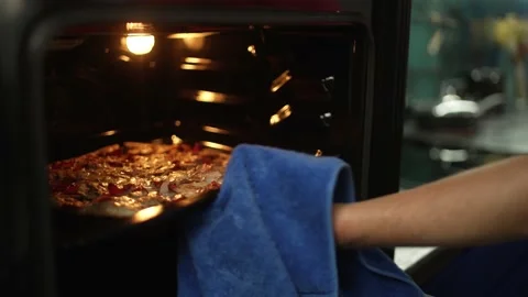 Reflection in the door of the oven from which hot pizza is taken out Stock Footage 228219628