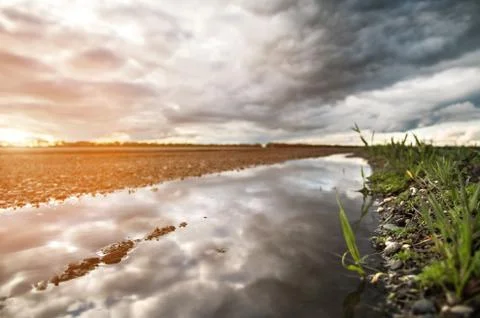 The reflection of the dramatic sky in a puddle on the side of a country road in Stock Photos