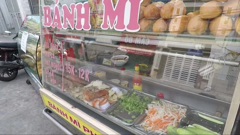 Reflection of driving bikes in glass case of street food stall, Ho Chi Minh City 库存影片 145632416