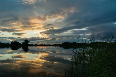 Reflection of the evening clouds in the lake water Stock Photos