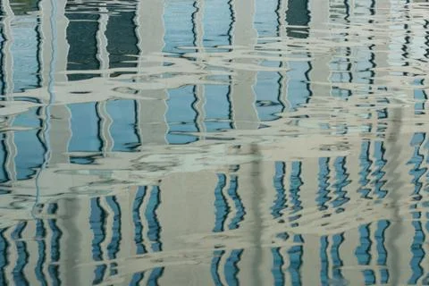 Reflection of the facade of a modern building on a wavy surface of the water Stock Photos
