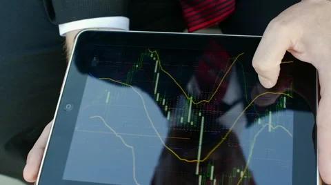 Reflection of the face of a businessman in a tablet that looks financial charts Stock Footage 50847075