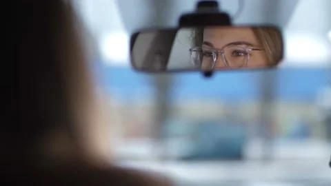 Reflection of female eyes in the front mirror of the car. Brown eyes with Stock Footage 100395032