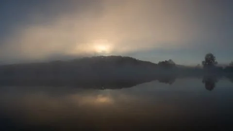 Reflection of the first rays of the sun in a misty forest lake Stock Photos