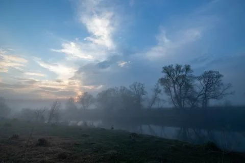 Reflection of the first rays of the sun in a misty forest lake Stock Photos