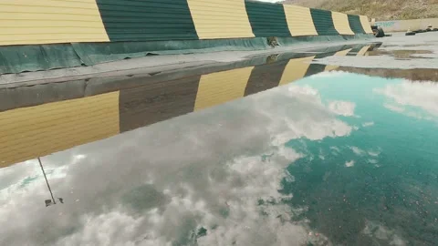 Reflection of flying clouds from the mirror surface of a puddle Stock-Footage 208186073