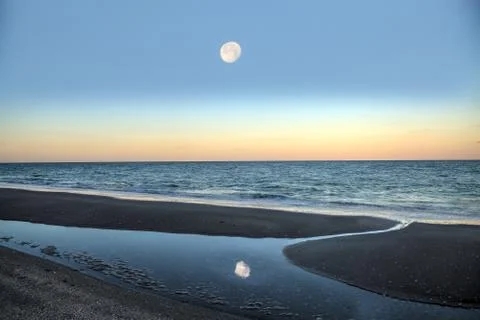 Reflection of the full moonset in a tidal pool in front of the ocean Foto stock