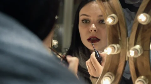 Reflection of girl applying her make-up. Brunette young woman putting lipstick Stock Footage 106747500