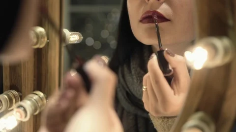 Reflection of girl applying her make-up. Brunette young woman putting lipstick Stock Footage 106748017