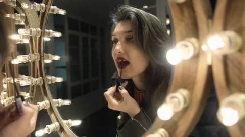 Reflection of girl applying her make-up. Brunette young woman putting lipstick Stock Footage 106748248