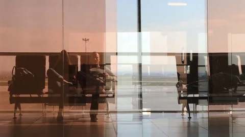 Reflection in the glass. The couple is waiting for their flight in airport Stock Footage 74331164