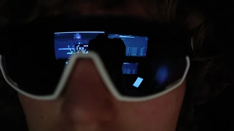 The reflection in the glasses shows multiple screens with video editing software Video stock 297112527