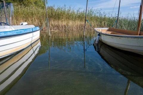 Reflection in green water between two small boats in a lake. Picture from Stock Photos