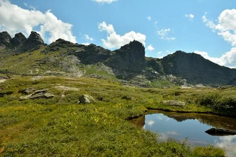 Reflection of high mountain ranges in the surface of a small beautiful lake.. Stock Photos