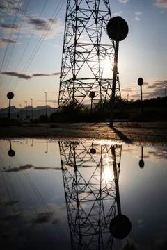 Reflection of a high voltage tower in a pond with the sky hidden behind on a  Stock Photos
